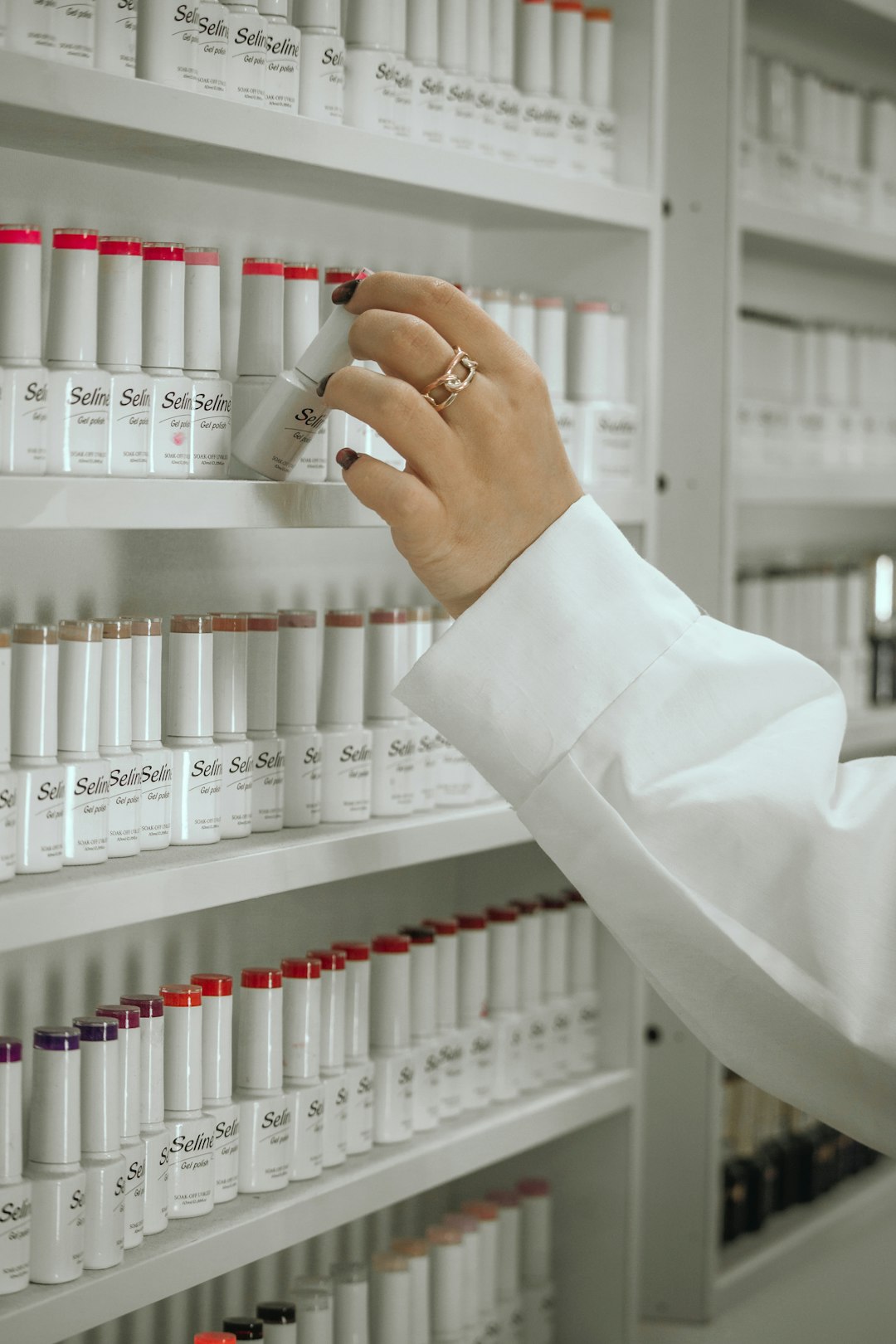 a-woman-in-a-white-lab-coat-is-looking-at-a-shelf-of-bottles-zie36uqrvka