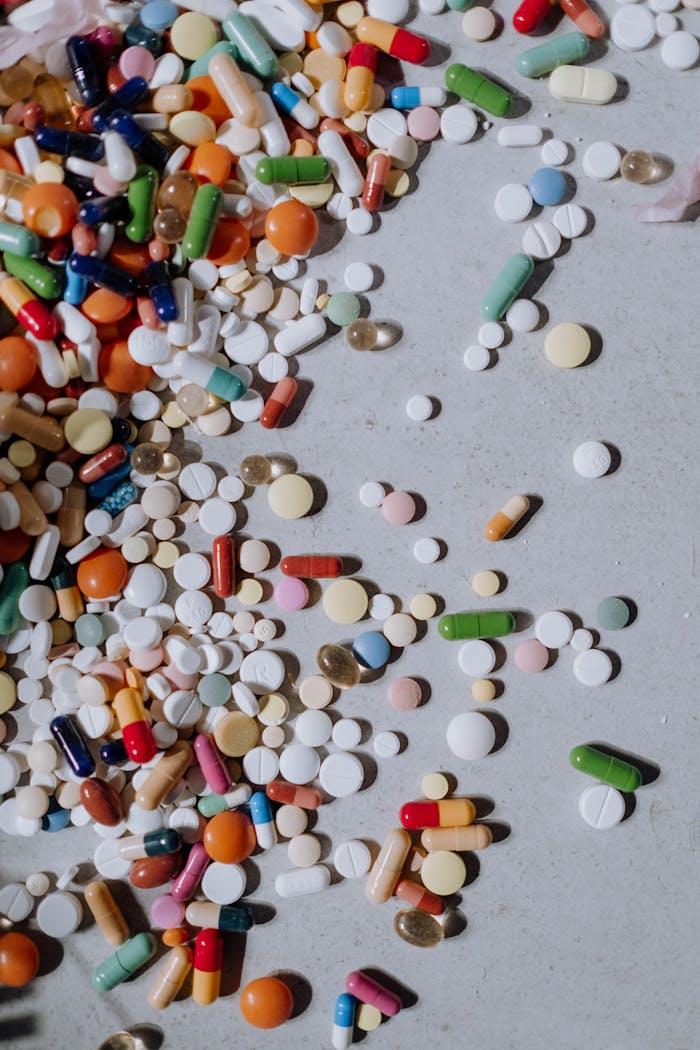 about-01 A diverse mix of pills and capsules scattered on a flat surface.