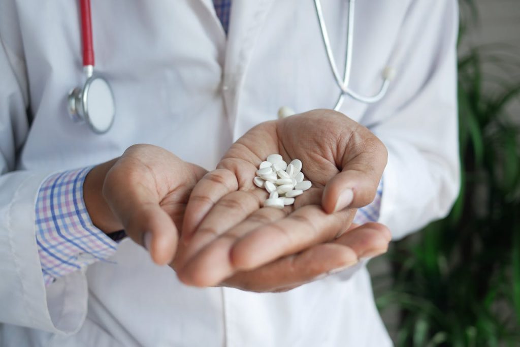 A close-up of a doctor holding white pills in their palms, emphasizing healthcare and medicine.