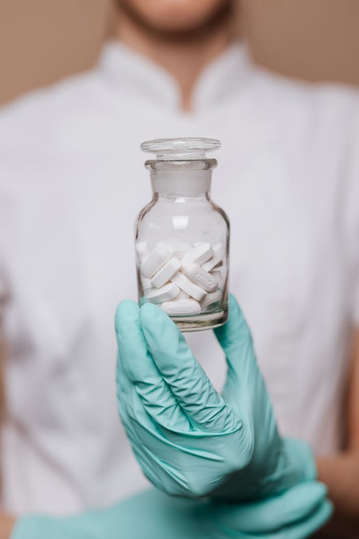 menu-07 A healthcare worker in gloves holding a clear bottle with pills, symbolizing medical care.